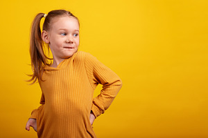 Young girl in a mustard sweater playfully looking over her shoul, a Person Photo by Ales Munt