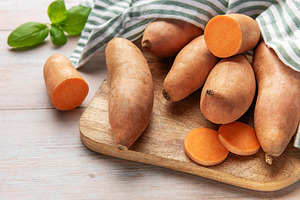 Sweet potatoes on wooden board with basil leaves, a Food & Drink Photo by Olena Rudo