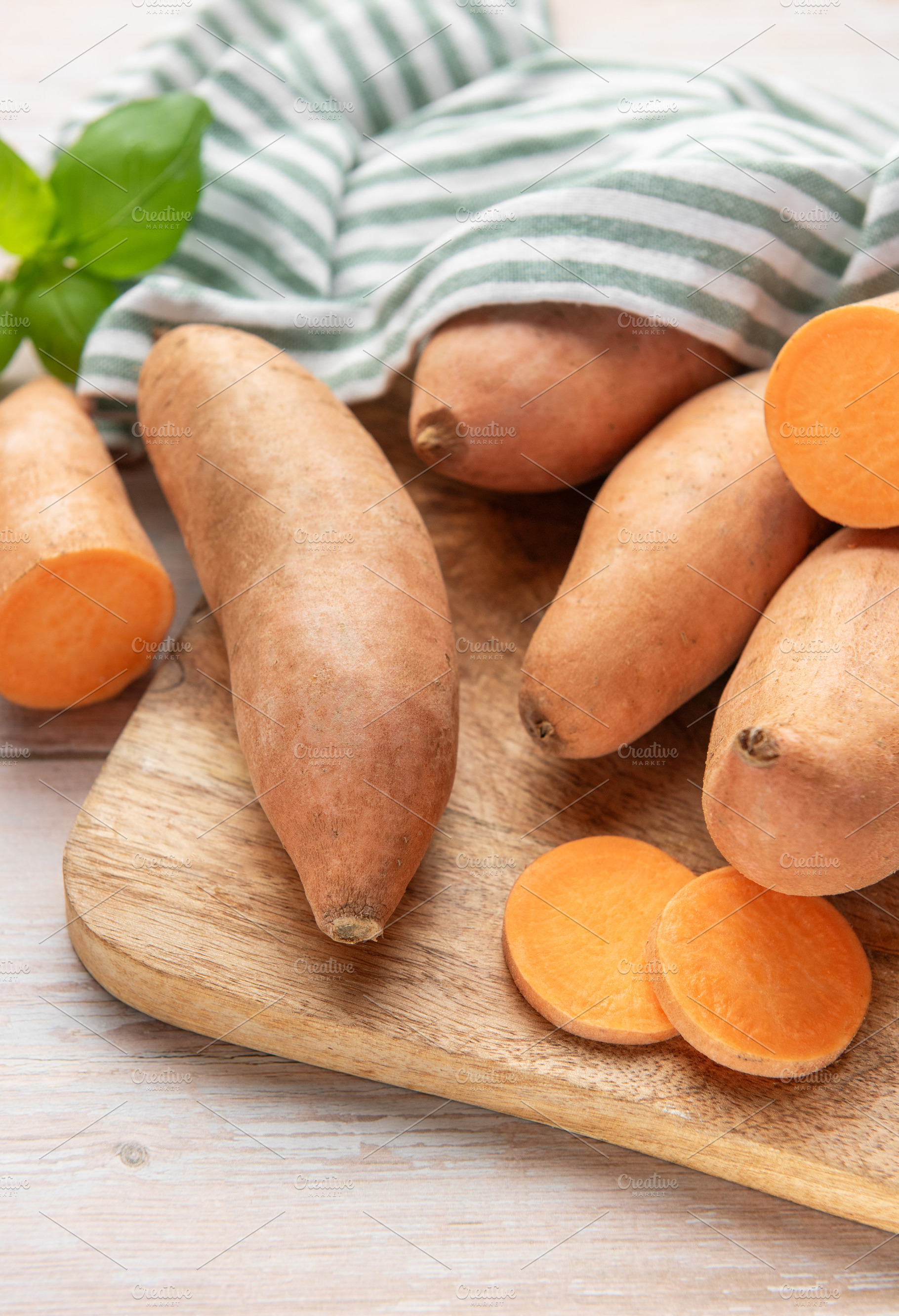 Whole and sliced sweet potatoes on wooden board, a Food & Drink Photo by Olena Rudo
