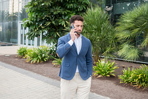 Businessman talking on smartphone while walking outside office, a Business Photo by etorres69