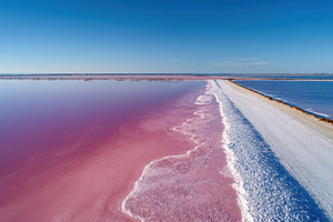 Aerial view of pink salt lake and dirt road, a Nature Photo by AlyaAnd