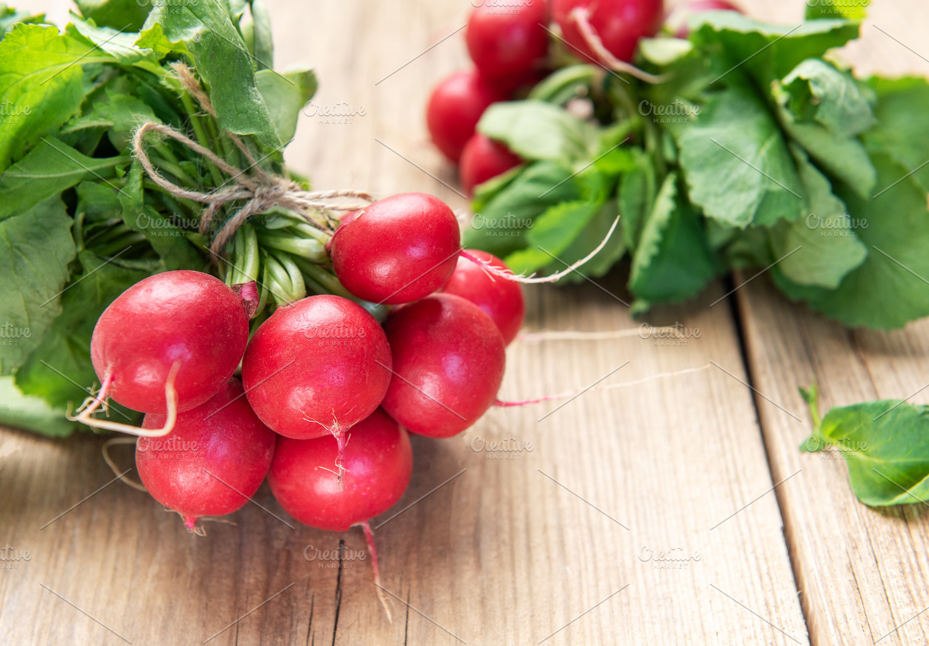 Fresh organic radishes with green leaves on rustic wood, a Food & Drink Photo by Olena Rudo