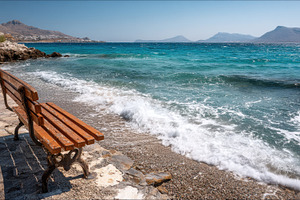 Bench sits on rocky shore, a Photo by Pavel_design