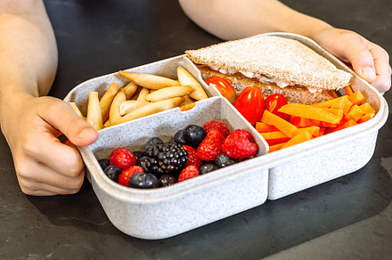 Unrecognizable girl taking lunch box filled with healthy food, a School & Education Photo by davidpereiras