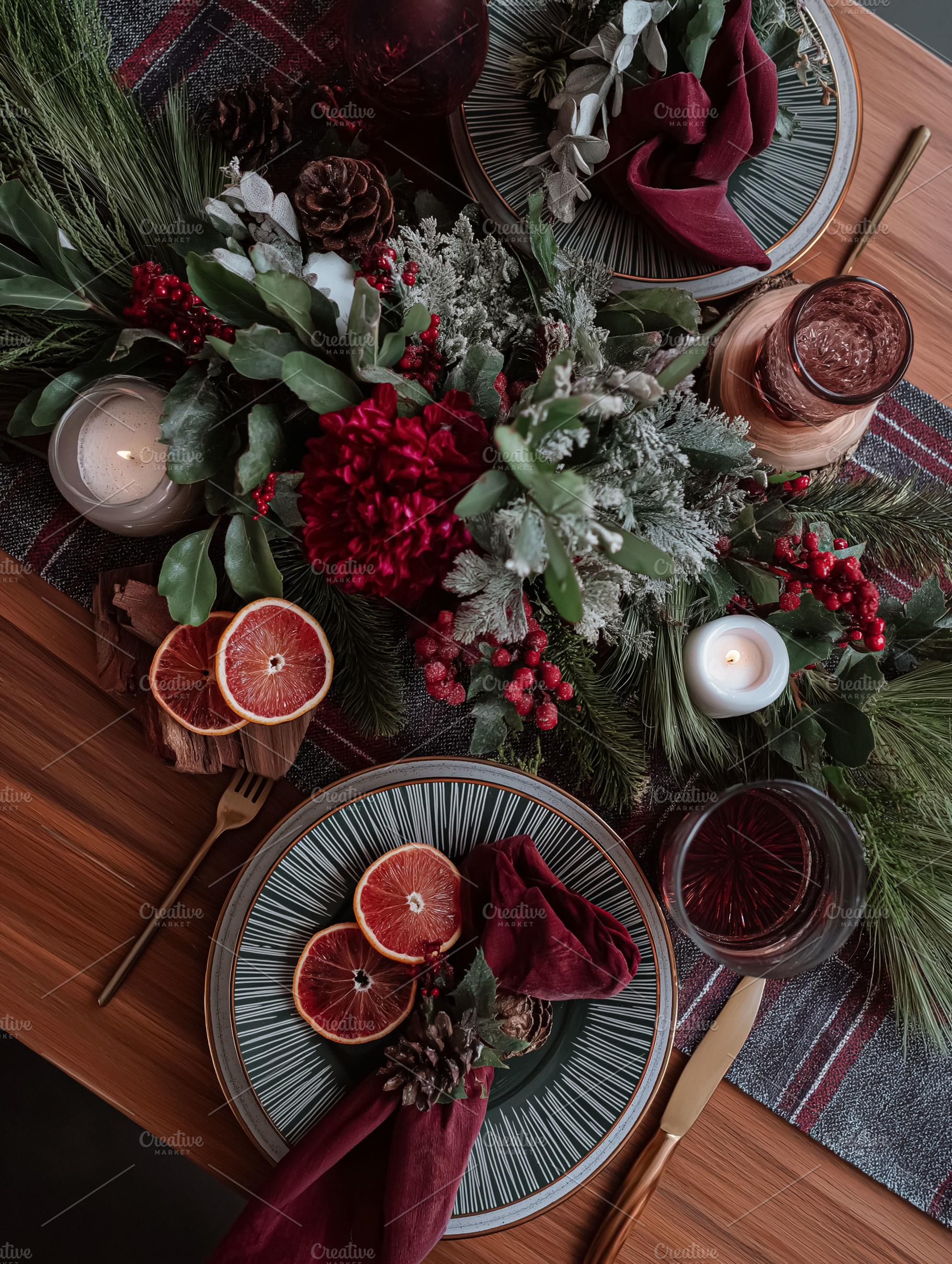 Elegant Christmas dinner table set with plaid runner, candles, pine, foliage, a, a Food & Drink Photo by Studio ANNA