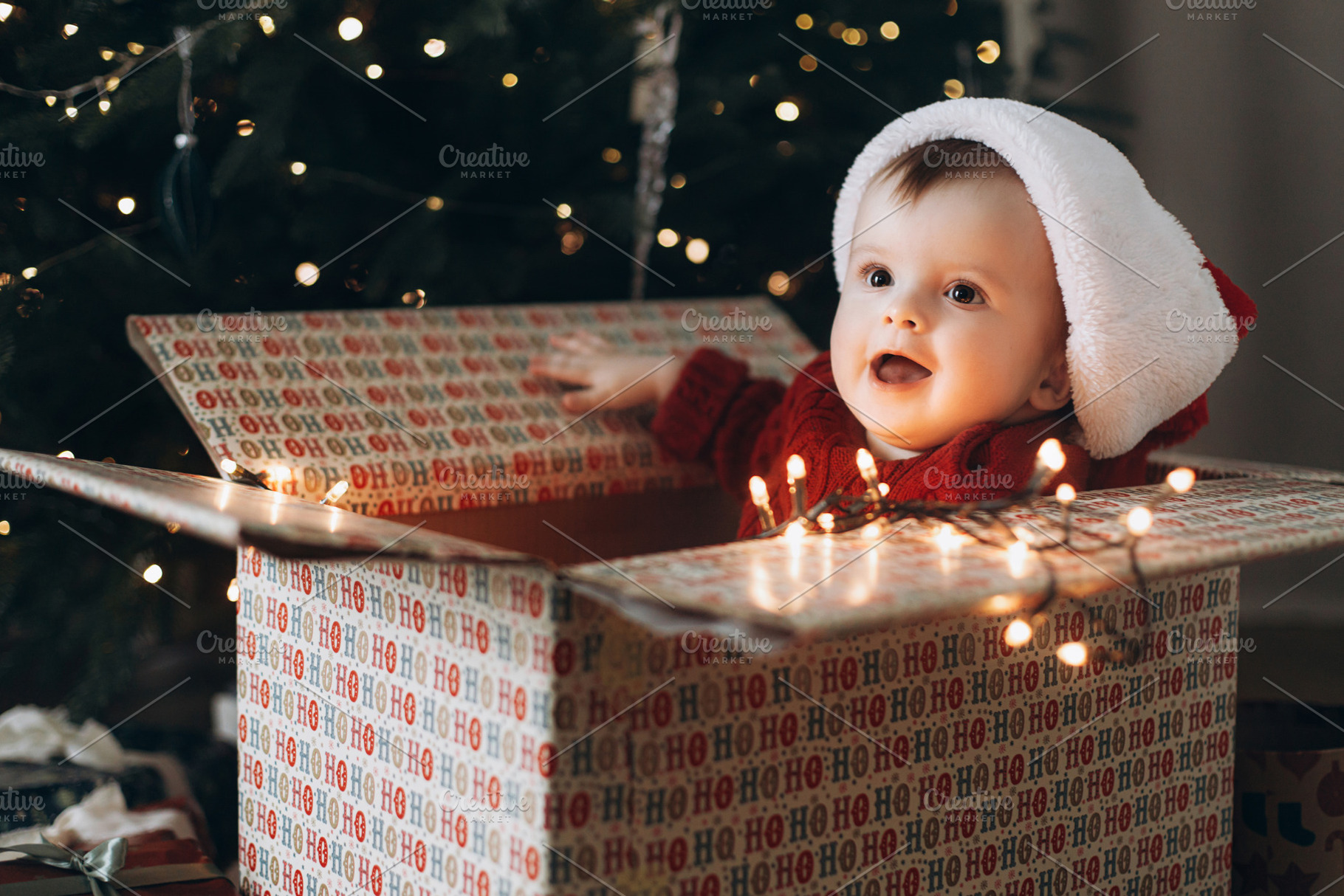 Adorable baby in santa hat sitting in big stylish present box wi, a Holiday Photo by Sonjachni