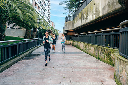 Women runners training over urban runway with palm trees