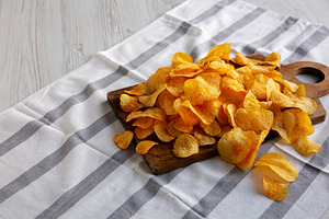 Homemade Flavored Cheese Potato Chips on a Wooden Board, side vi, a Food & Drink Photo by LiudmylaChuhunova