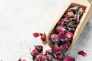 Dried rose buds spilling from wooden scoop, a Food & Drink Photo by Olena Rudo