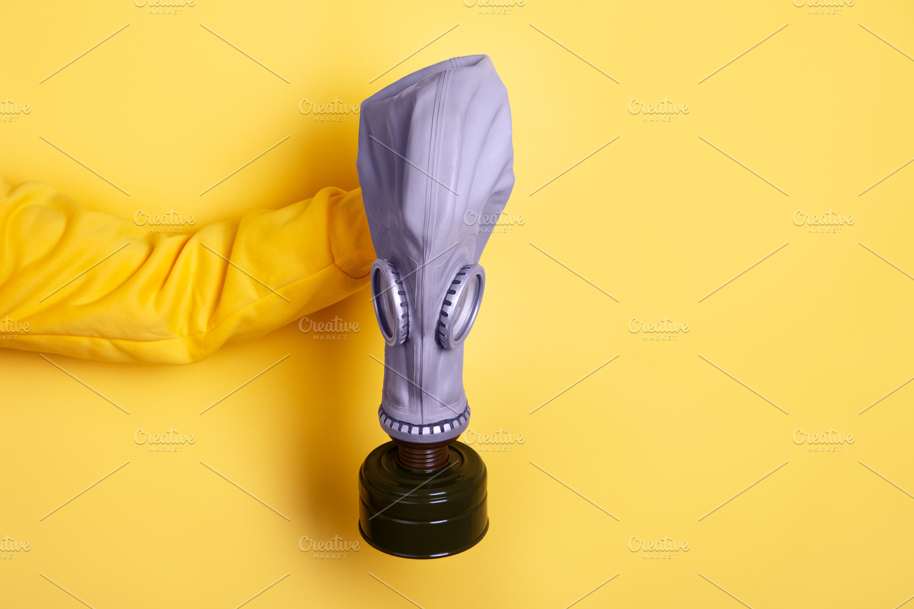 Person in yellow sleeve holds purple gas mask against a vibrant, a Person Photo by Ales Munt