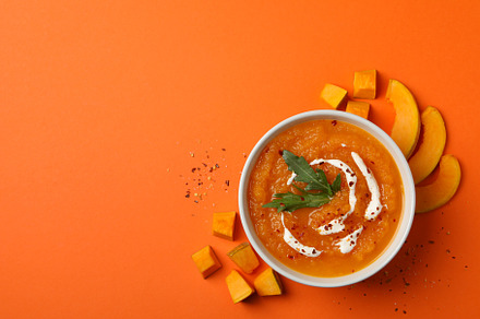 Pumpkin cream soup on orange background, top view, a Food & Drink Photo by AtlasStudio
