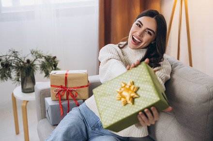 Beautiful happy woman unwrapping New Year or Christmas presents
