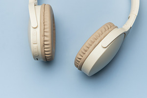 Modern wireless headphones lying on minimalist blue background, a Technology Photo by Olena Rudo