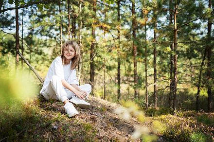 Young girl enjoying a sunny day in a forest clearing while sitti, a Person Photo by Olena Rudo