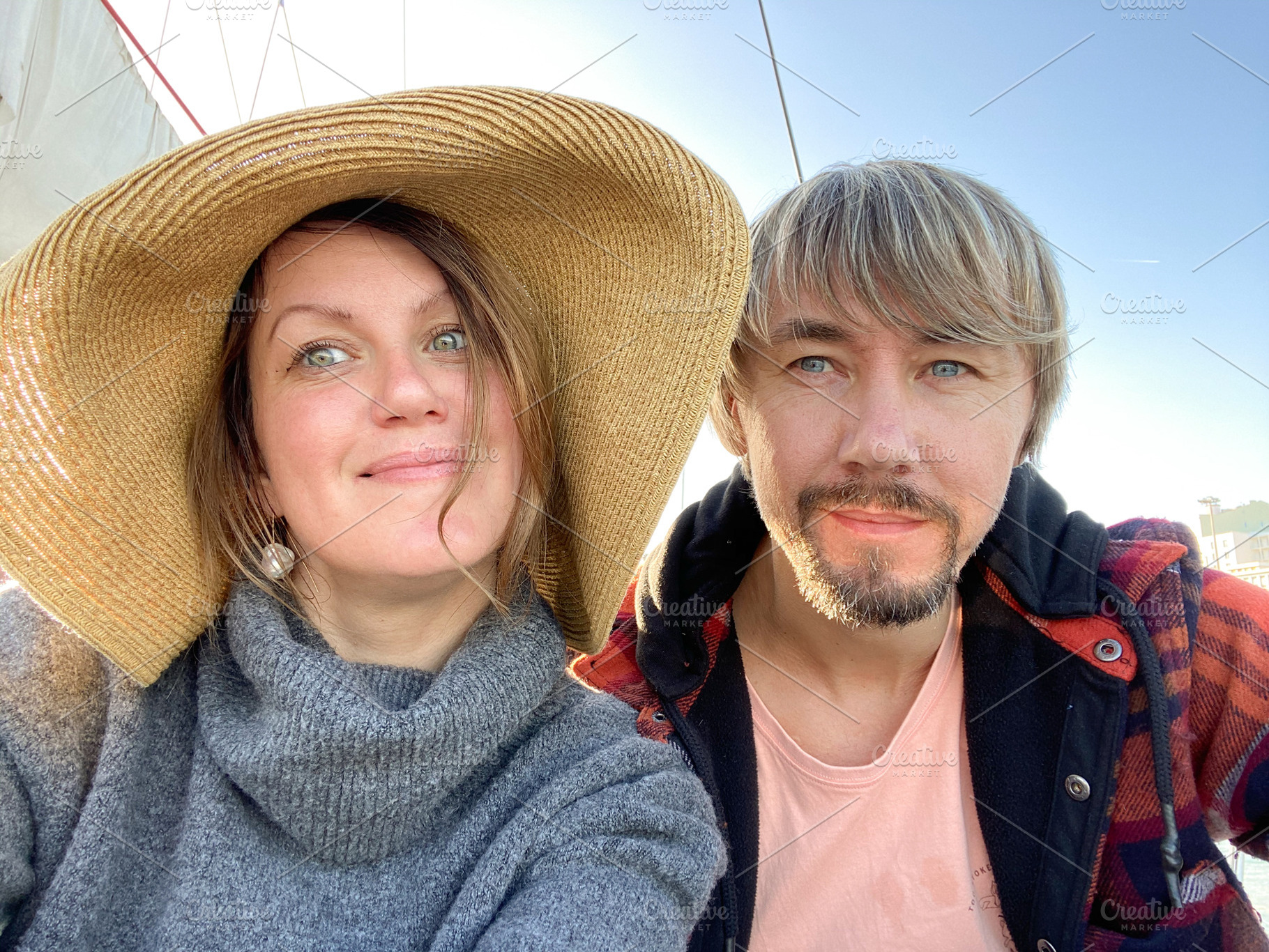 Smiling man and woman taking a close-up selfie under clear blue, a Person Photo by sebastianaraw