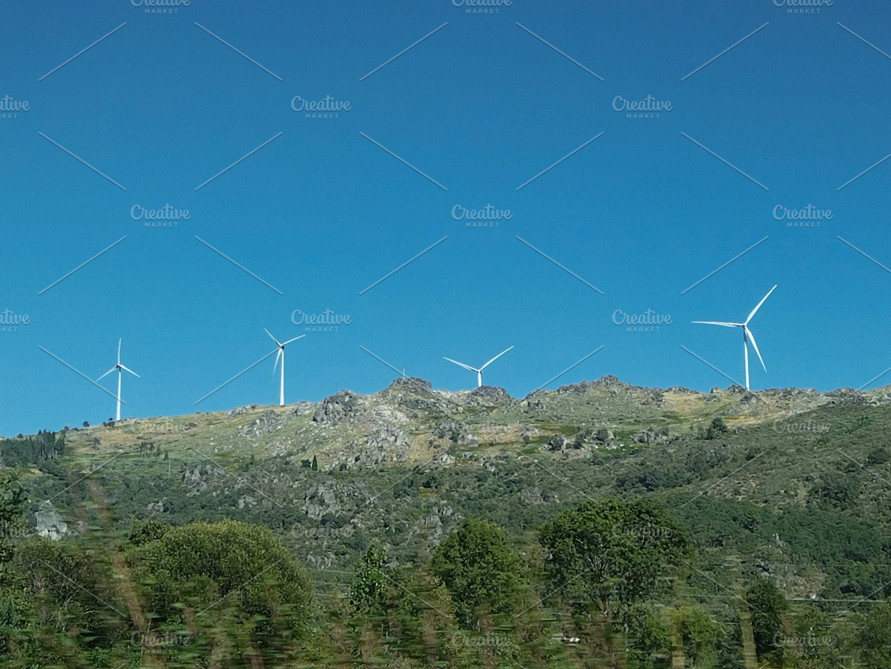 Wind turbines on green hills under blue sky, vila real, portugal, a Photo by DanFLCreativo