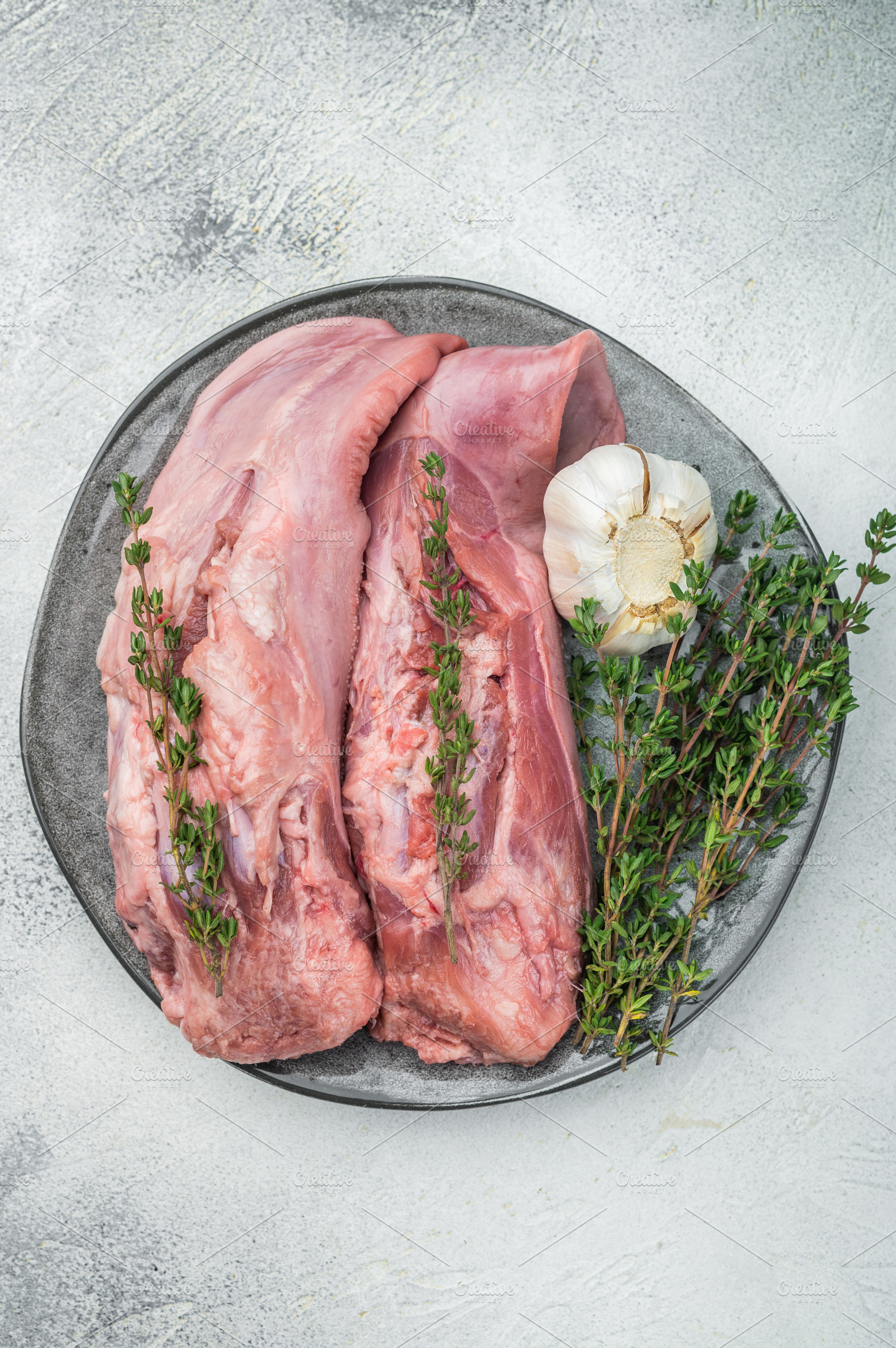 Raw lamb tongues on ceramic plate with thyme and garlic isolated, a Food & Drink Photo by composter-box@mail.ru