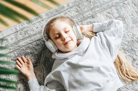 Little girl listening music lying on the floor, a Person Photo by Olena Rudo