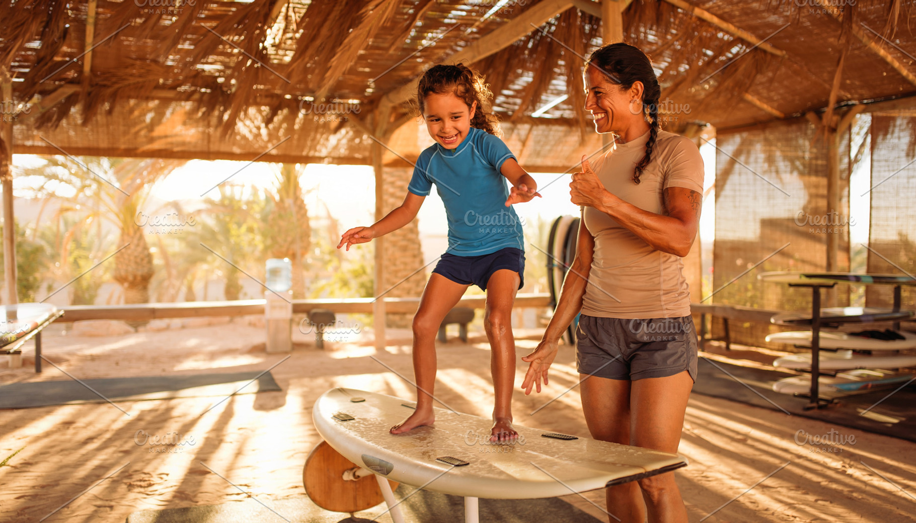 Girl balancing on a surfboard in a wooden beach shelter, a Person Photo by DanFLCreativo