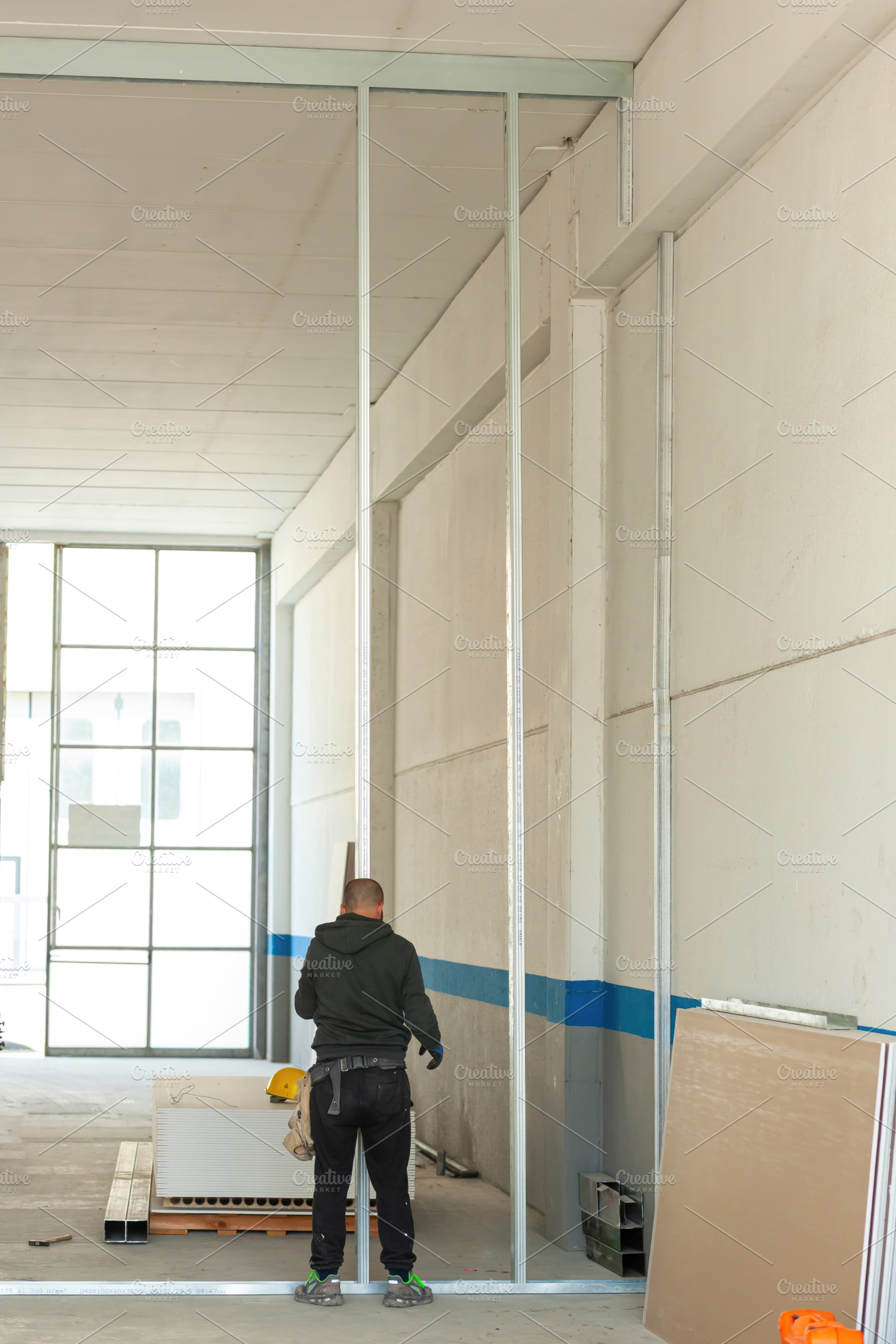 Construction worker installing aluminum pillars for plasterboard wall in indust, an Industrial Photo by Antonio Gravante Market