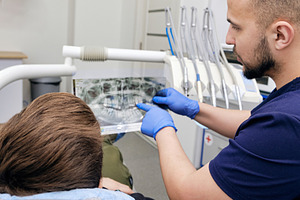 Dentist showing panoramic X-ray to a patient. Male dentist in blue gloves point, a Health & Medical Photo by Rohan Photography