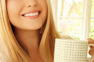 Young blonde woman smiling, holding coffee mug, enjoying morning, a Person Photo by Studio ANNA