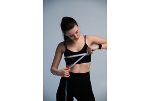 Young woman measuring her body with, a Sports & Recreation Photo by volodymyrshtun13795
