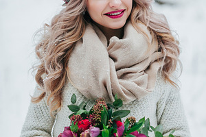 Beautiful smiling girl of Slavic appearance with a wreath of wildflowers holds a bouquet in winter background.