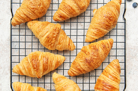 Freshly baked croissants cooling on a wire rack with honey and b