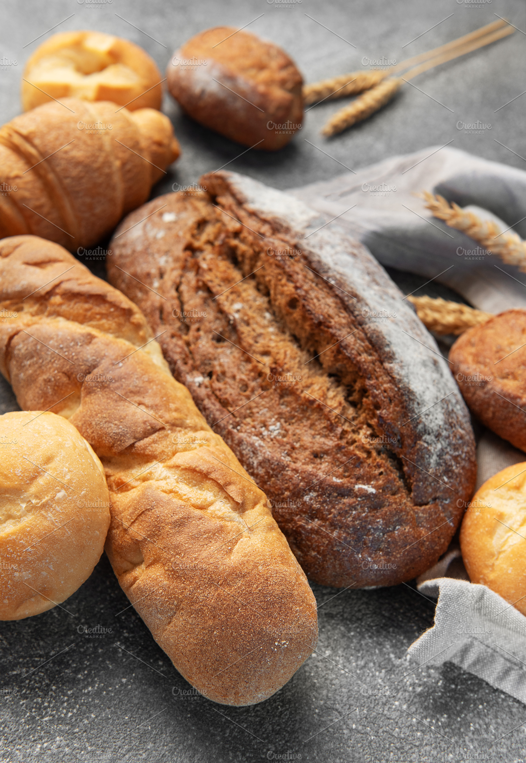 Freshly baked bread assortment with wheat ears on rustic backgro, a Food & Drink Photo by Olena Rudo
