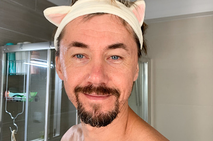 Portrait of a man in a bathroom wearing a playful cat ear headba