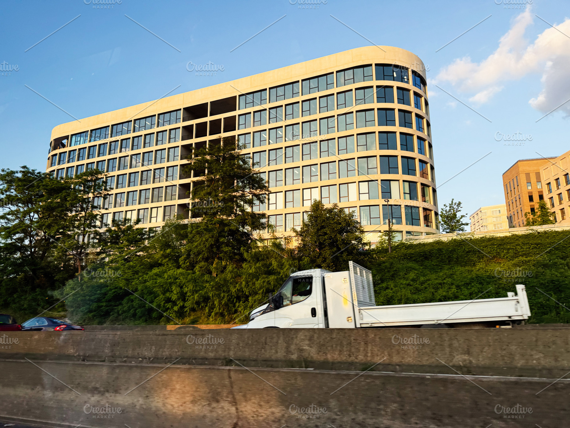 Modern office building with glass facade and delivery truck on highway in Paris, a Photo by AS photostudio