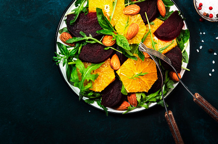 Beet Salad with orange, arugula and almonds on blue table backgr, a Food & Drink Photo by 5PH