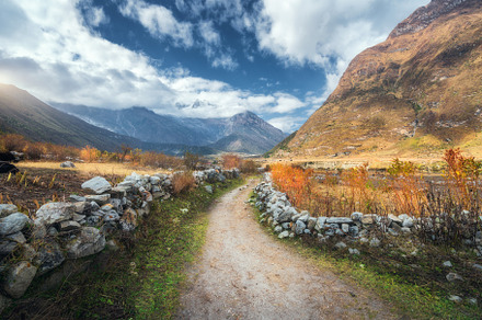 Dirt road at sunset in summer in Himalayan mountains, a Nature Photo by den-belitsky