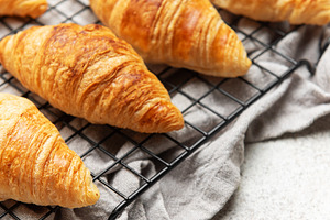 Freshly baked croissants cooling on wire rack, perfect start to, a Food & Drink Photo by Olena Rudo