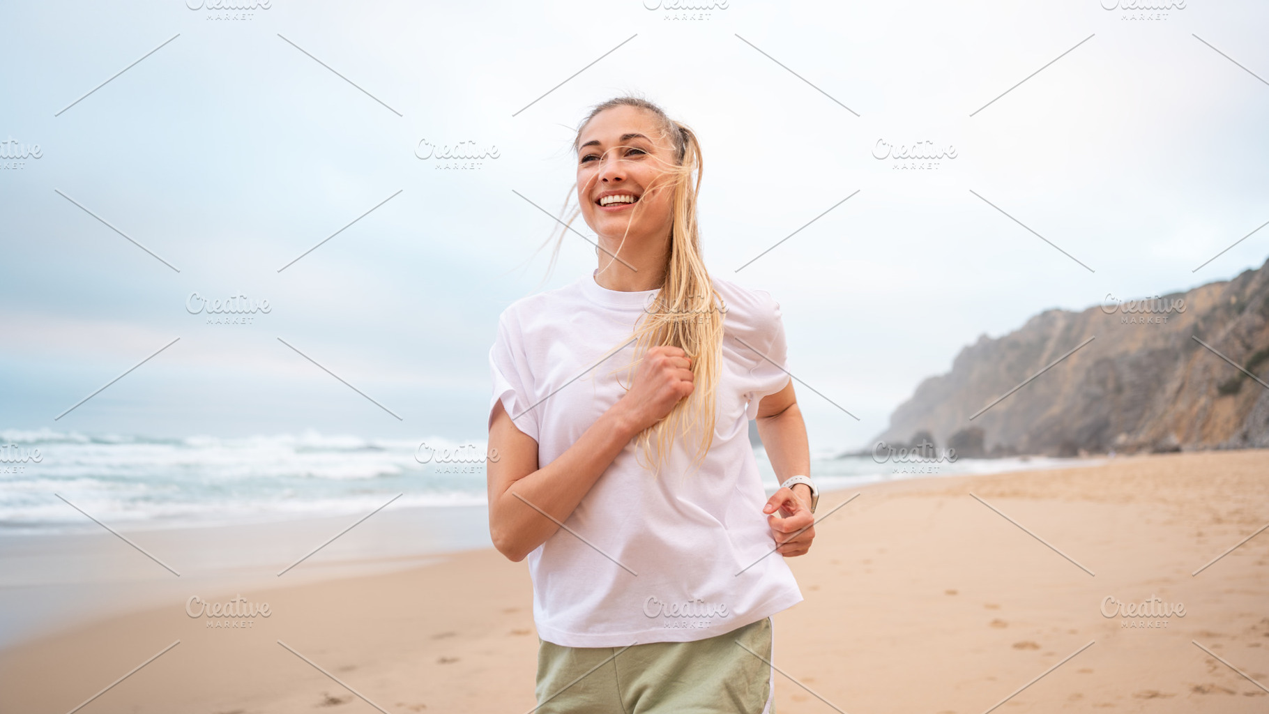 Smiling young woman runner jogging on sandy beach near sea, a Person Photo by andreonegin market