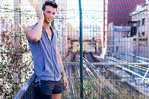Young man listening to music by urban fence, a Person Photo by RF Images