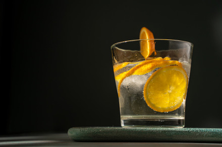 Glass of gin tonic with orange slice and ice. dark green backgro, a Food & Drink Photo by SZ IMAGE
