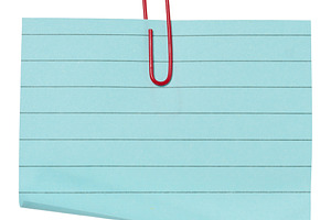 A sheet of blue lined paper attached with a red paper clip on an, a Background Photo by ndanko