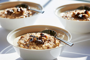 Oat porridge bowls topped with dried fruit and nuts, offering a nutritious and, a Photo by Studio ANNA