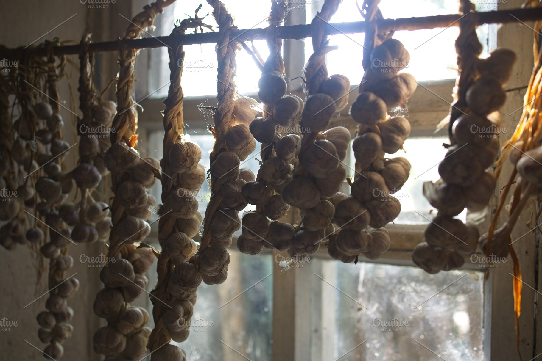 braided garlic hanging from the window, a Food & Drink Photo by TanaCh