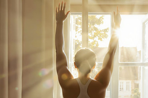 Woman stretching in front of a windo, a Person Photo by Perpis