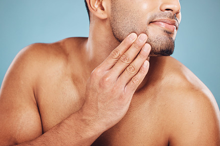 Man, beard care and hands on face after grooming, fresh and clean shave isolated on blue studio background. Beauty, skincare and wellness of male model, good facial hygiene routine and healthy skin., a Photo by Peopleimages.com