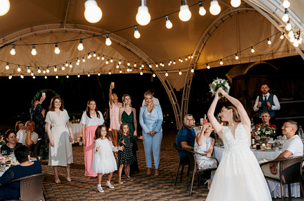 bride in a white dress throws a wedding bouquet