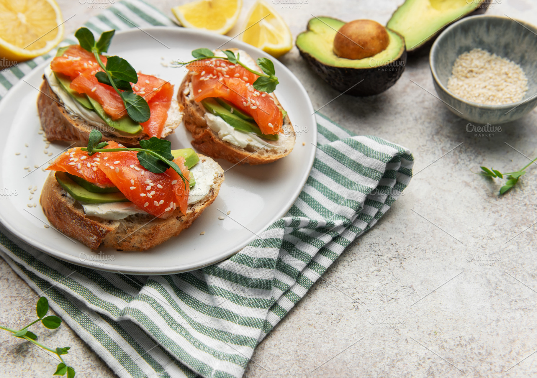 Preparing avocado salmon toasts with sesame seeds and lemon, a Food & Drink Photo by Olena Rudo