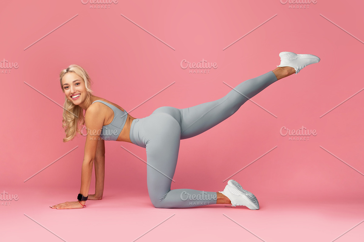 Smiling Young Woman Doing Exercise With Leg Raise, a Photo by Prostock-Studio (Photo 1 of 2)