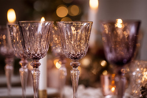 Crystal wine glasses on a festive table setting with candlelight, a Photo by Studio ANNA