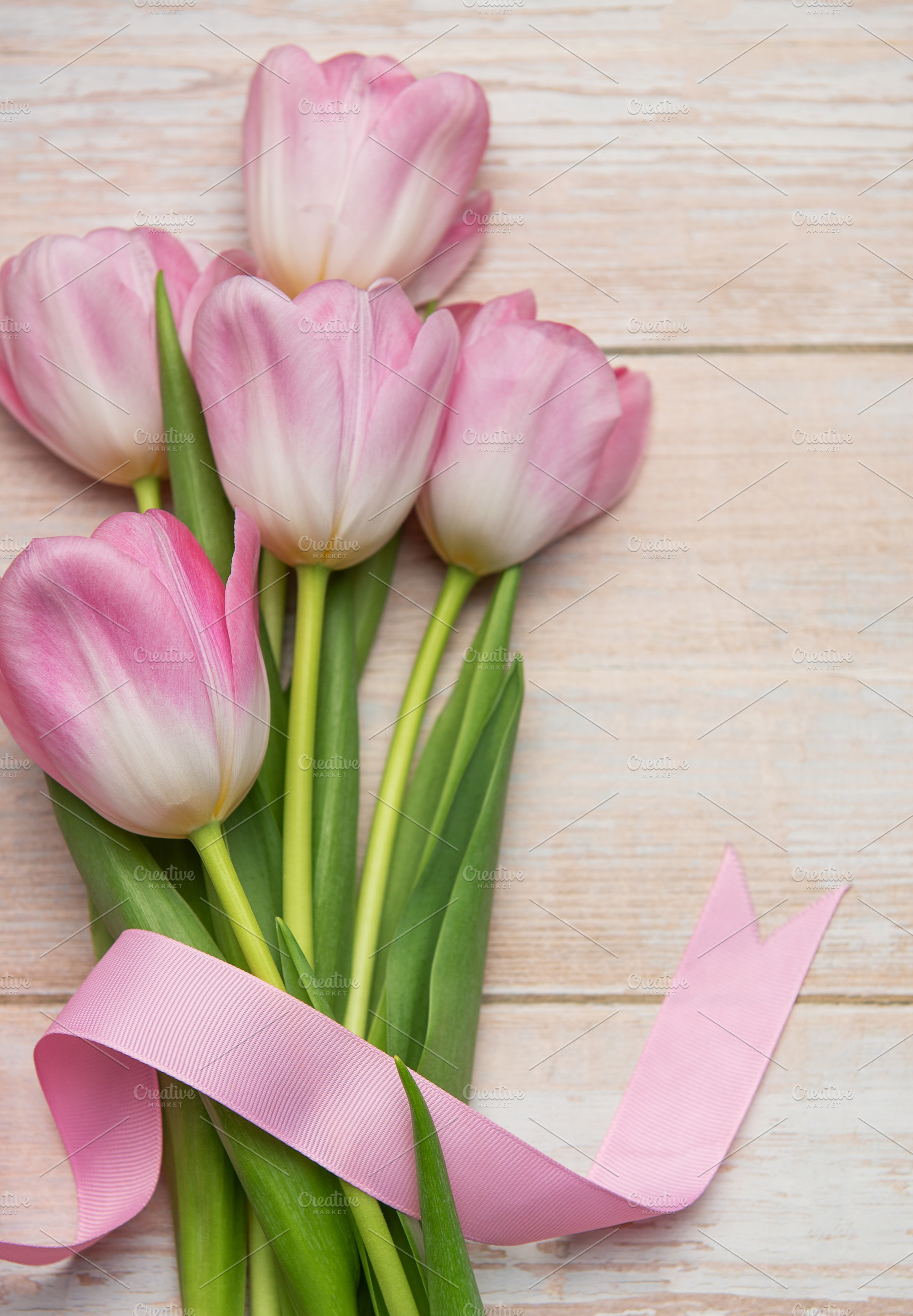 Bouquet of pink tulips tied with pink ribbon on wooden table, a Holiday Photo by Olena Rudo