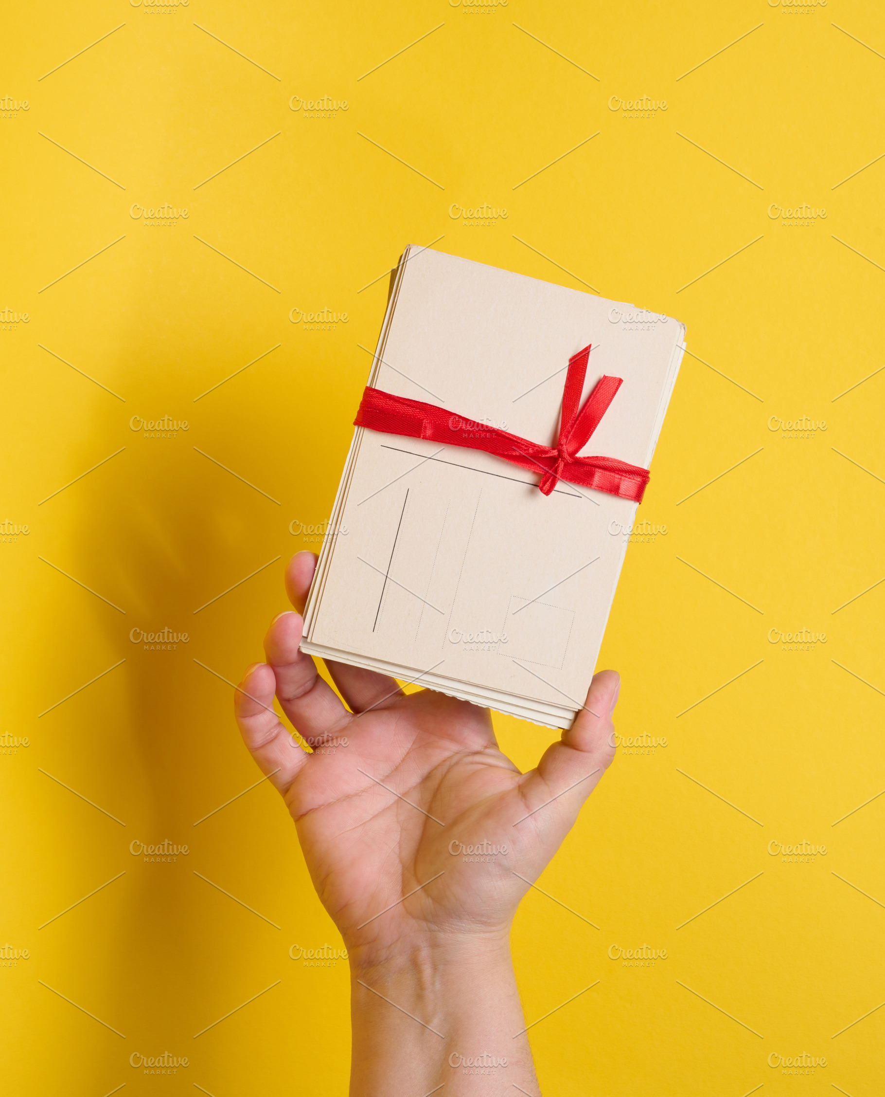 A person holding a stack of vintage postcards tied with a red ri, a Holiday Photo by ndanko