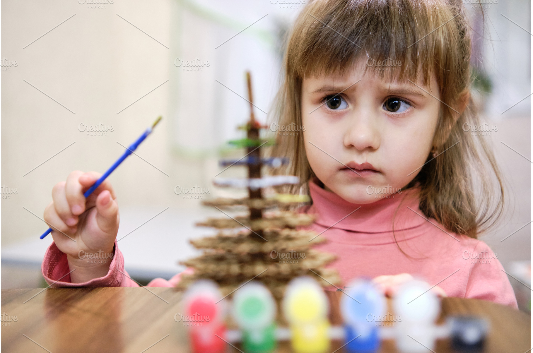A little girl paints a wooden toy in, a Holiday Photo by Rohan Photography